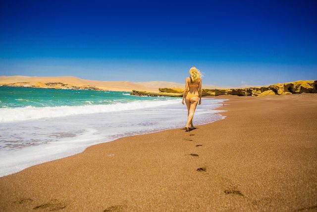 Nazca Lines Day Trip – Tourist walking along the red sands of Playa Roja in Paracas.