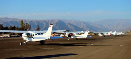 Small aircraft lined up at Nazca Airport with mountains in the background