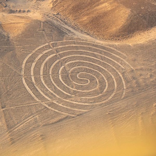 Aerial view of a large spiral geoglyph etched into the desert floor near the Nazca hills