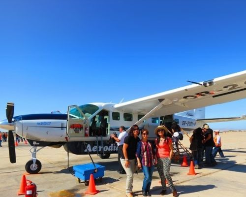 Passengers posing beside a Cessna Grand Caravan at Pisco Airport