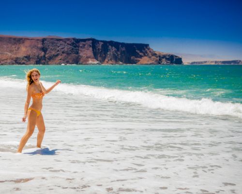 Smiling woman playing in the waves on Paracas beach