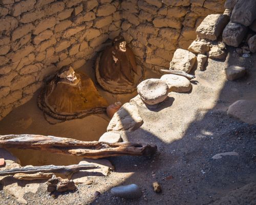 Two ancient mummies seated inside a stone-lined tomb.