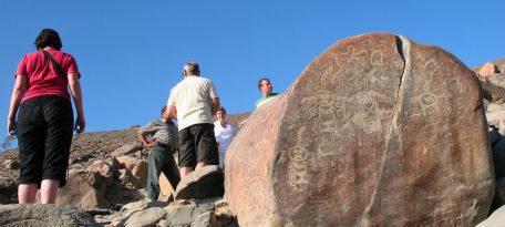 Tourists examining a carved stone panel during the Chichictara Petroglyphs Tour.