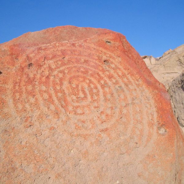 Spiral petroglyph carved into a reddish volcanic rock.