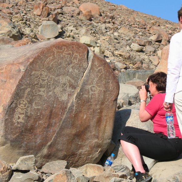Tourists photographing petroglyphs of ancient priest figures.